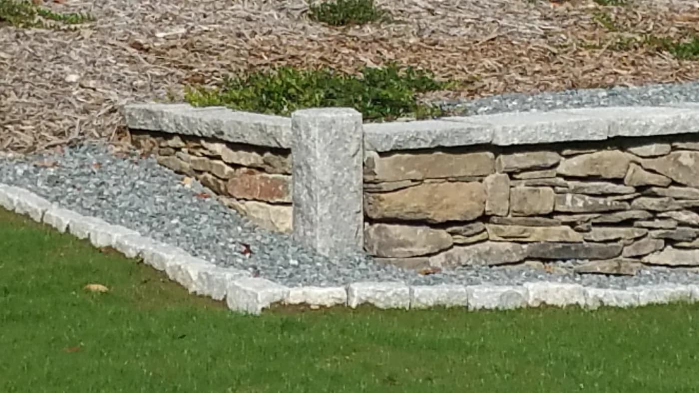 Dry-stack natural stone retaining wall with granite cap and post