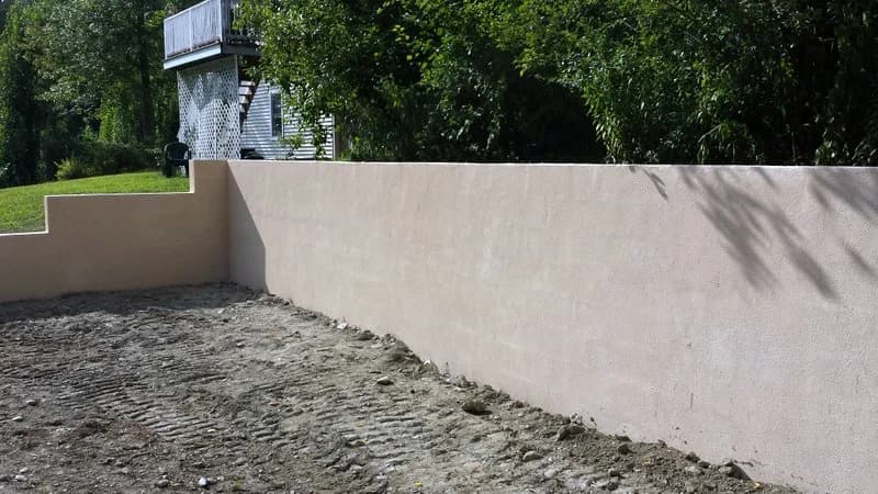 Smooth parged concrete retaining wall with a stepped end
