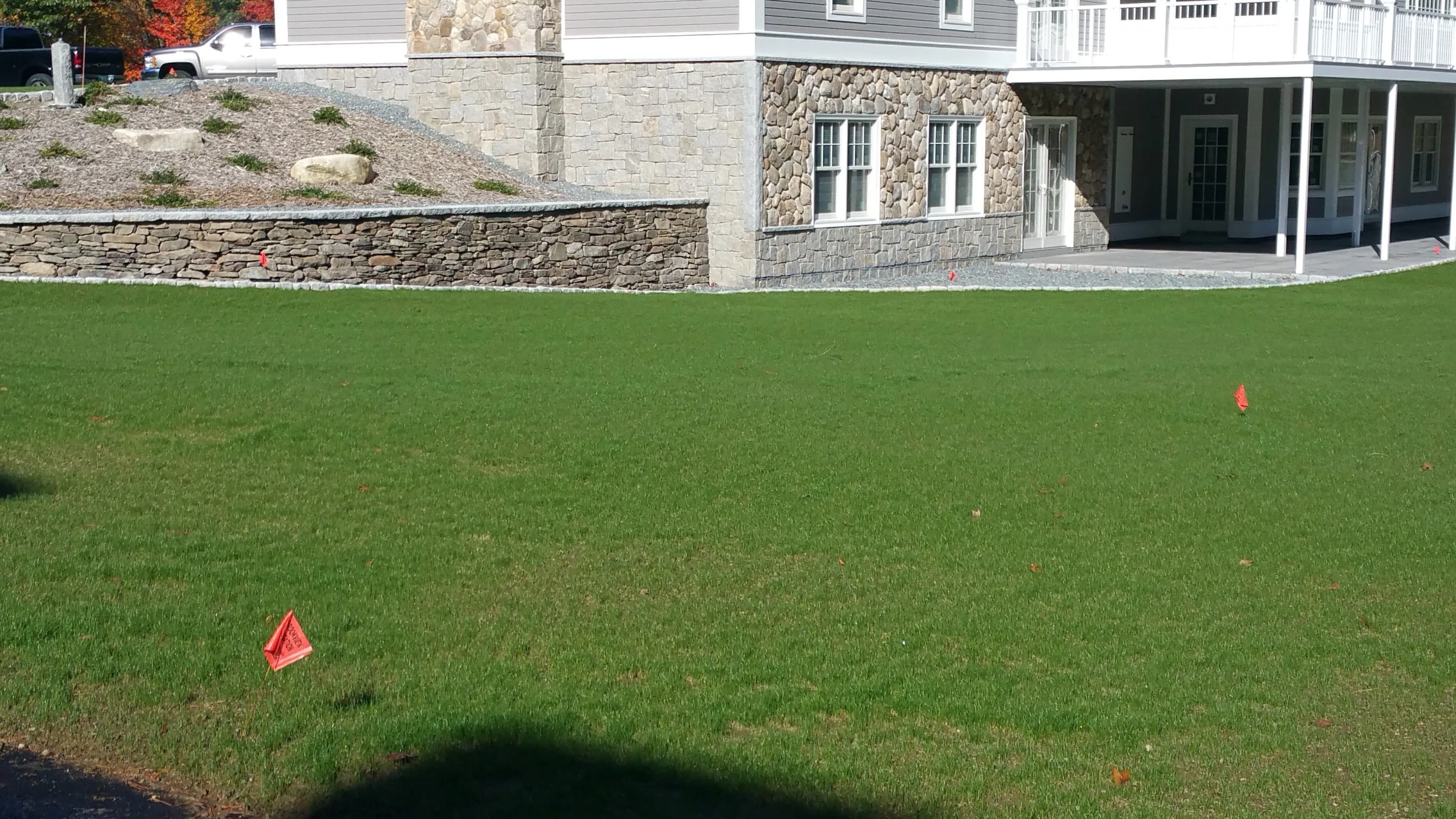 Building with mixed stone veneer — ledgestone retaining wall, rectangular block foundation, and rounded fieldstone around windows and entry column