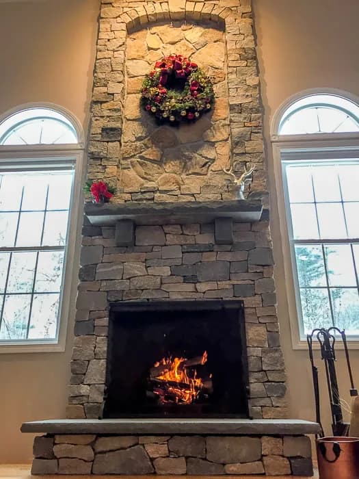 Floor-to-ceiling natural stone fireplace with a lit fire
