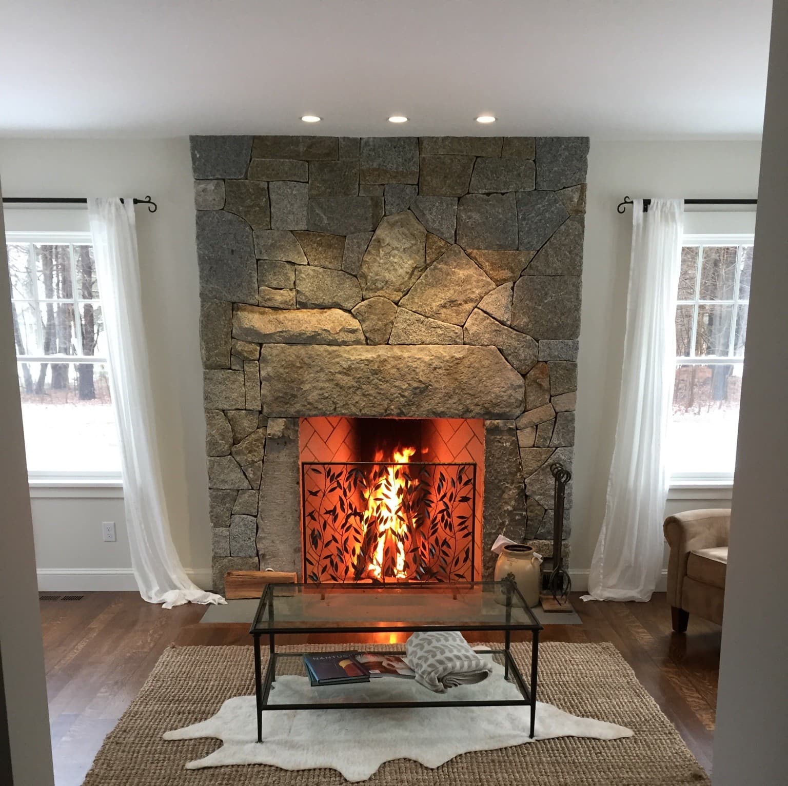 Completed natural-stone fireplace with a granite lintel and a lit fire