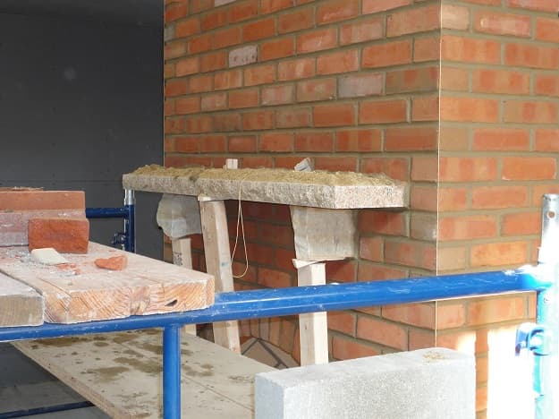 Stone mantle being set on a Rumford fireplace
